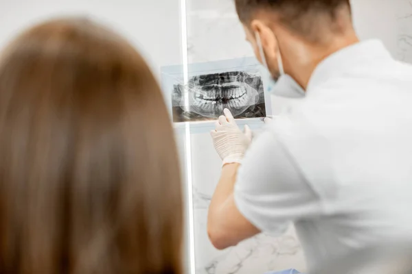 Zahnarzt zeigt Röntgenbild eines Kiefers für junge Patientin — Stockfoto