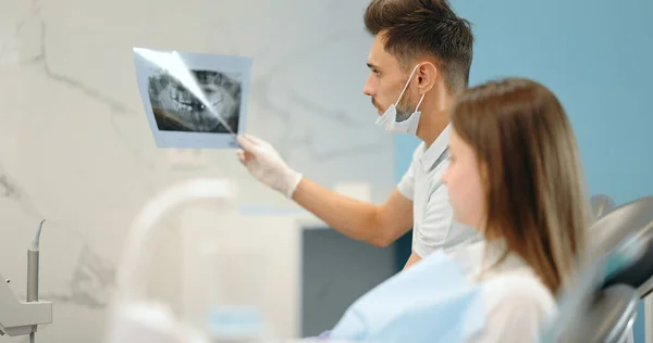 Dentista mostrando raio-X de uma mandíbula para um paciente jovem — Fotografia de Stock