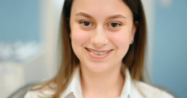在牙科诊所里一个戴牙套的快乐女孩的画像 — 图库照片