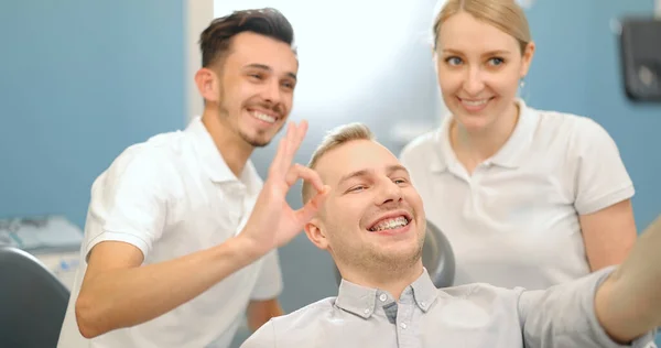 Счастливый пациент с дантистом в стоматологическом кабинете — стоковое фото