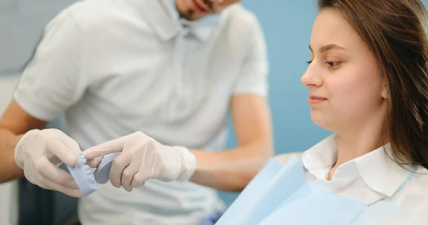 年轻病人的牙科医生显示颌骨模型 — 图库照片