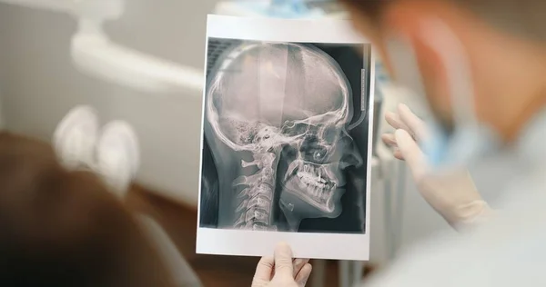 Tannlege som viser røntgen av en skalle for en ung pasient – stockfoto