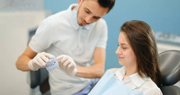 Dentista mostrando modelo de mandíbula para um paciente jovem — Fotografia de Stock