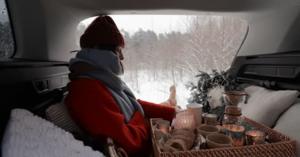 Γυναίκα που κάνει πικ-νικ σε πορτ-μπαγκάζ αυτοκινήτου σε χιονισμένο δάσος — Αρχείο Βίντεο