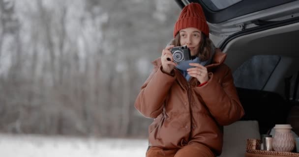 Kvinna med fotokamera i en bil bagageutrymme, reser under en vintersemester — Stockvideo