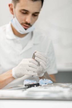 Diş teknisyeni bir diş ve diş teli modeli üzerinde çalışıyor.
