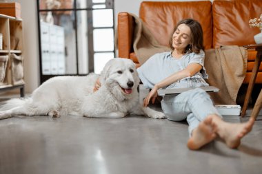 Evde çalışan bir kadın köpekle oturuyor.
