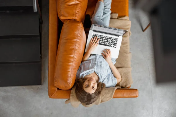 Donna che lavora con laptop da casa sul divano — Foto Stock