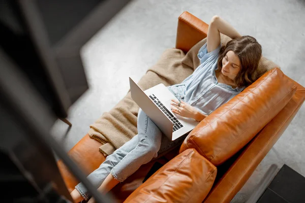 Donna che lavora con laptop da casa sul divano — Foto Stock