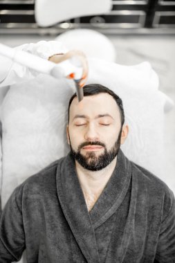 Güzellik kliniğinde kozmetik uzmanı lazer yüz gerdirme ameliyatı yapıyor.