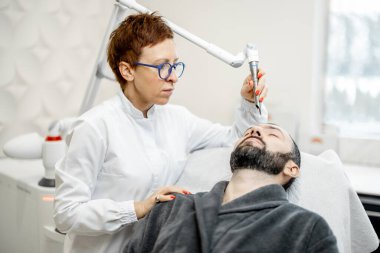 Güzellik kliniğinde kozmetik uzmanı lazer yüz gerdirme ameliyatı yapıyor.