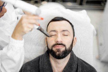 Güzellik kliniğinde kozmetik uzmanı lazer yüz gerdirme ameliyatı yapıyor.