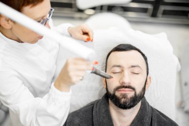 Güzellik kliniğinde kozmetik uzmanı lazer yüz gerdirme ameliyatı yapıyor.