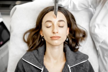 Güzellik kliniğinde kozmetik uzmanı lazer yüz gerdirme ameliyatı yapıyor.