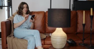 Işığı evde akıllı bir telefonla kontrol eden kadın.