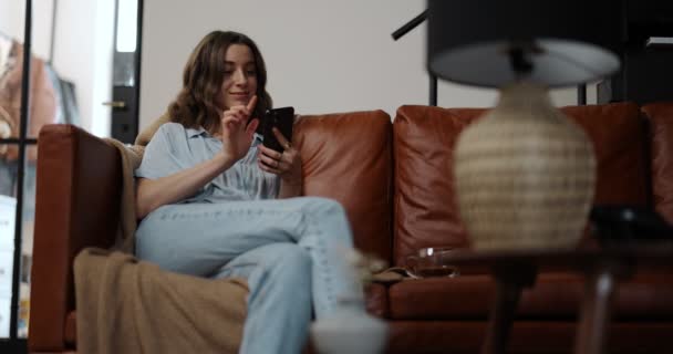 Kvinnlig kontroll ljus med en smart telefon hemma — Stockvideo