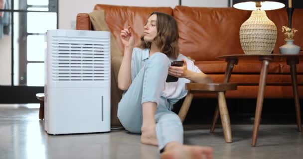 Женщина с очистителем воздуха или кондиционером дома — стоковое видео