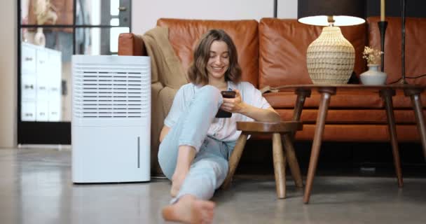 Женщина с очистителем воздуха или кондиционером дома — стоковое видео