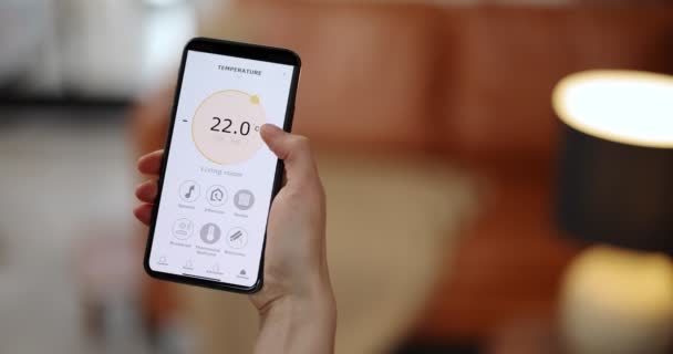 Femme ajustant la température ambiante avec un téléphone intelligent — Video