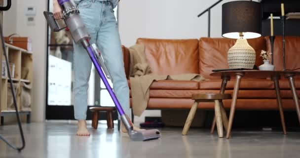 Женщина пылесосит пол беспроводным чистящим средством — стоковое видео