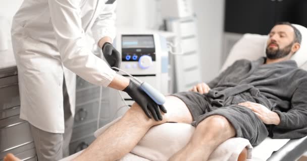 Doctor doing magnetic therapy on male knee — Stock Video