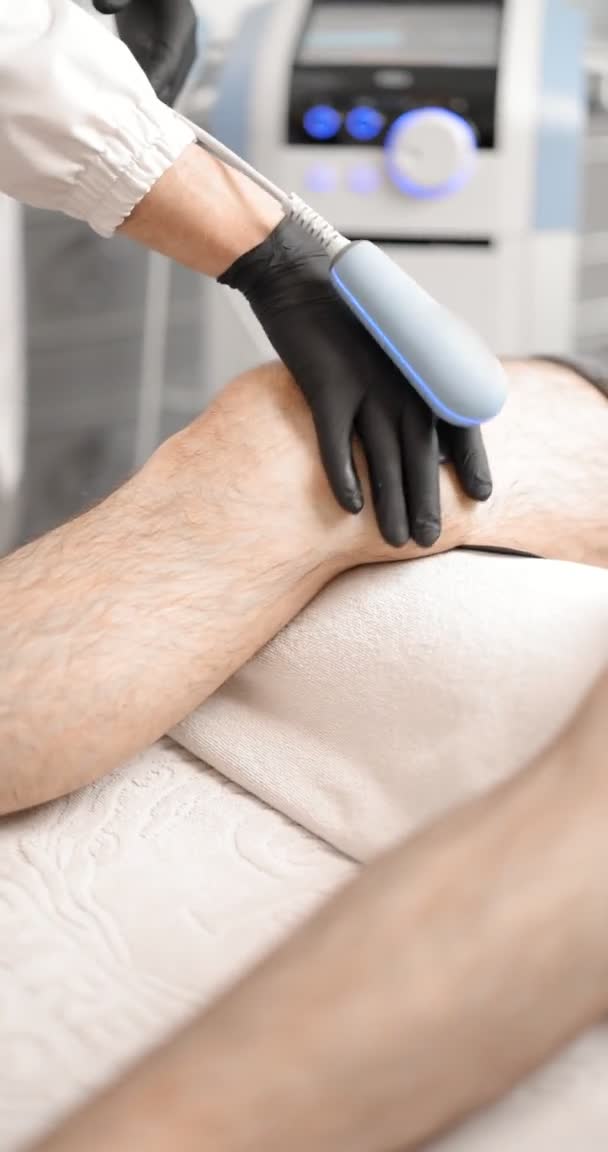 Doctor doing magnetic therapy on male knee — Stock Video