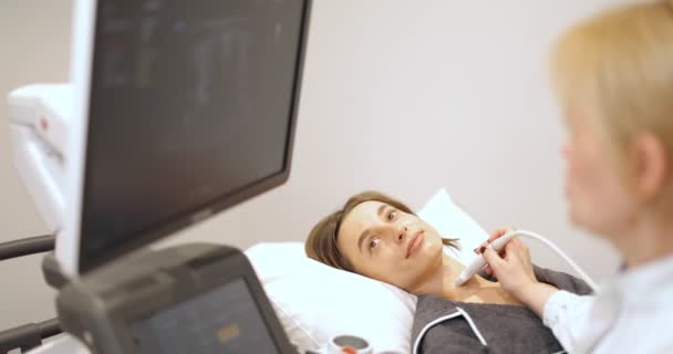 Médecin examinant la thyroïde d'une patiente avec échographie en clinique — Video