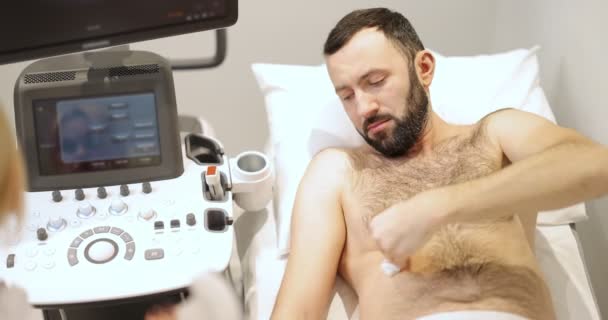 Lekarz badający wątrobę męskiego pacjenta z USG w klinice — Wideo stockowe