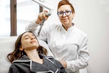 Güzellik kliniğinde kozmetik uzmanı lazer yüz gerdirme ameliyatı yapıyor.