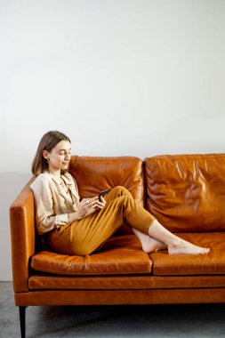 Evin arka planında Akıllı Telefon kullanan kadın.