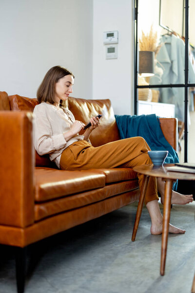 Woman sitting on the sofa at home with smartphone