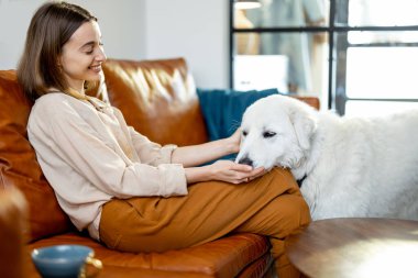 Evde bir köpekle kanepede oturan bir kadın..
