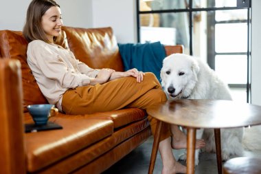 Evde bir köpekle kanepede oturan bir kadın..