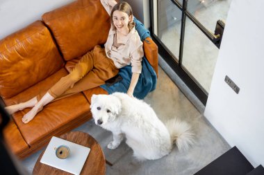 Evde bir köpekle kanepede oturan bir kadın..