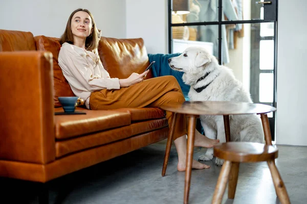 Evde bir köpekle kanepede oturan bir kadın..