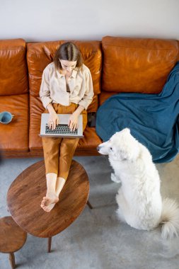 Evde bir köpekle kanepede oturan bir kadın..