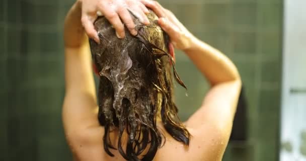 Женщина моет волосы в душе — стоковое видео