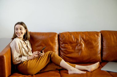 Evin arka planında Akıllı Telefon kullanan kadın.