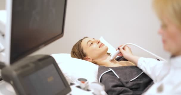 Médico examinando tireóide de paciente do sexo feminino com ultra-som na clínica — Vídeo de Stock