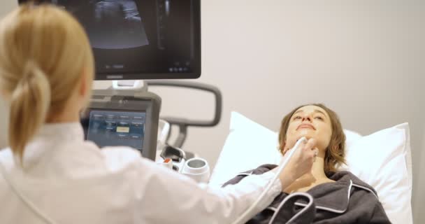 Лікар вивчення щитовидної залози пацієнта з ультразвуковим скануванням у клініці — стокове відео