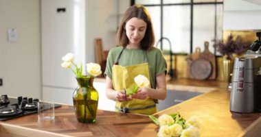 Kadın evin içini bir buket taze çiçekle süslüyor.