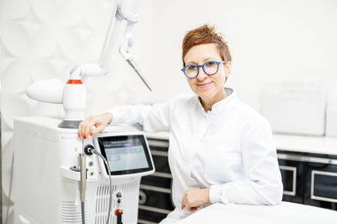 Güzellik kliniğindeki lazer tedavi cihazının yanındaki kozmetolog.