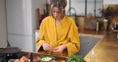 Kahvaltı için yumurta pişiren kadın.