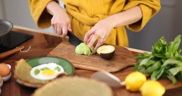 Žena připravuje snídani s vejci a avokádem — Stock video