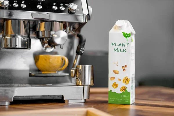Packaging of vegetable milk near a cup of coffee