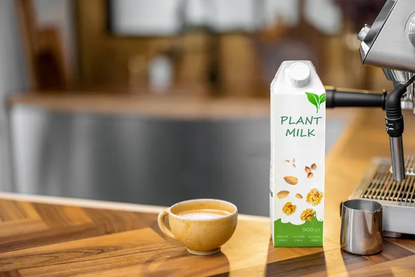 Packaging of vegetable milk near a cup of coffee