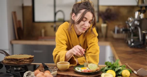 Mujer disfruta del desayuno en la cocina por la mañana — Vídeos de Stock
