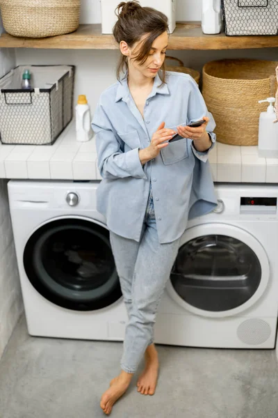 Femme avec téléphone dans la buanderie — Photo