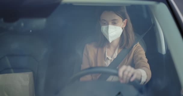 Женщина снимает маску во время вождения автомобиля — стоковое видео
