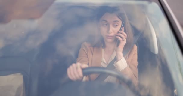 Zakelijke vrouw praat over de telefoon tijdens het besturen van een auto — Stockvideo